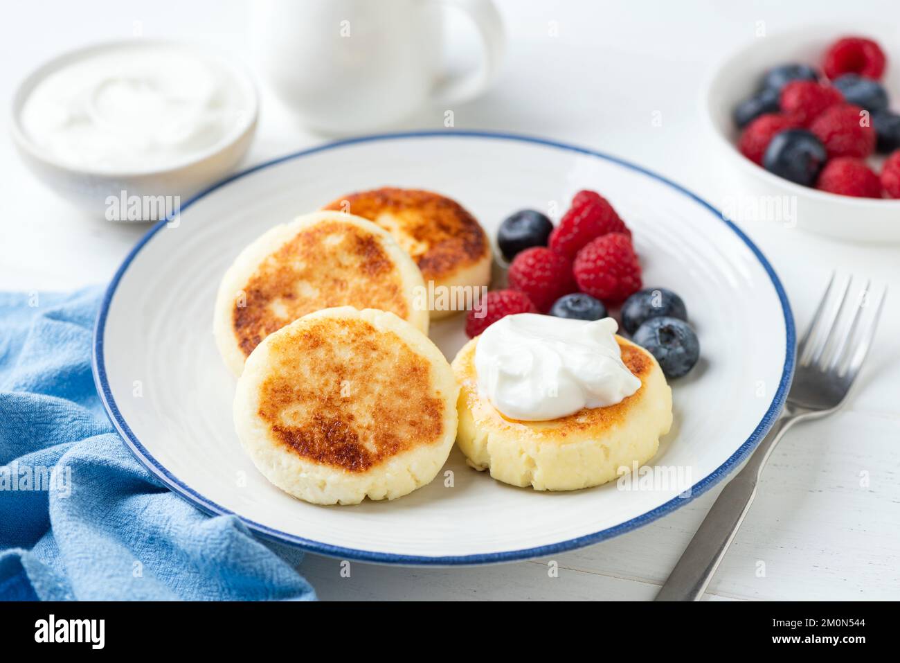 Sweet cottage cheese fritters Syrniki served with berries and greek yogurt. Dessert or healthy breakfast food Stock Photo