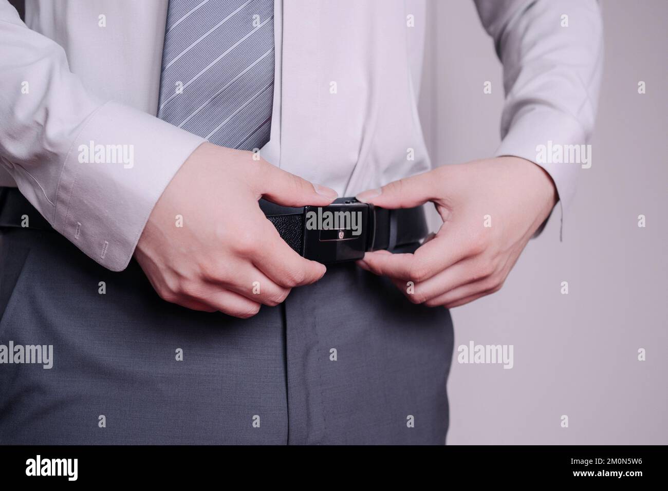 A closeup of the hands of a groom fixing his belt Stock Photo