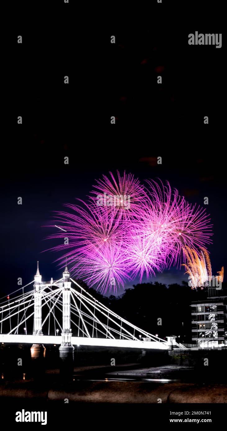 A vertical shot of fireworks over Albert Bridge in Battersea Park, London, on weekend night by bonfire Stock Photo