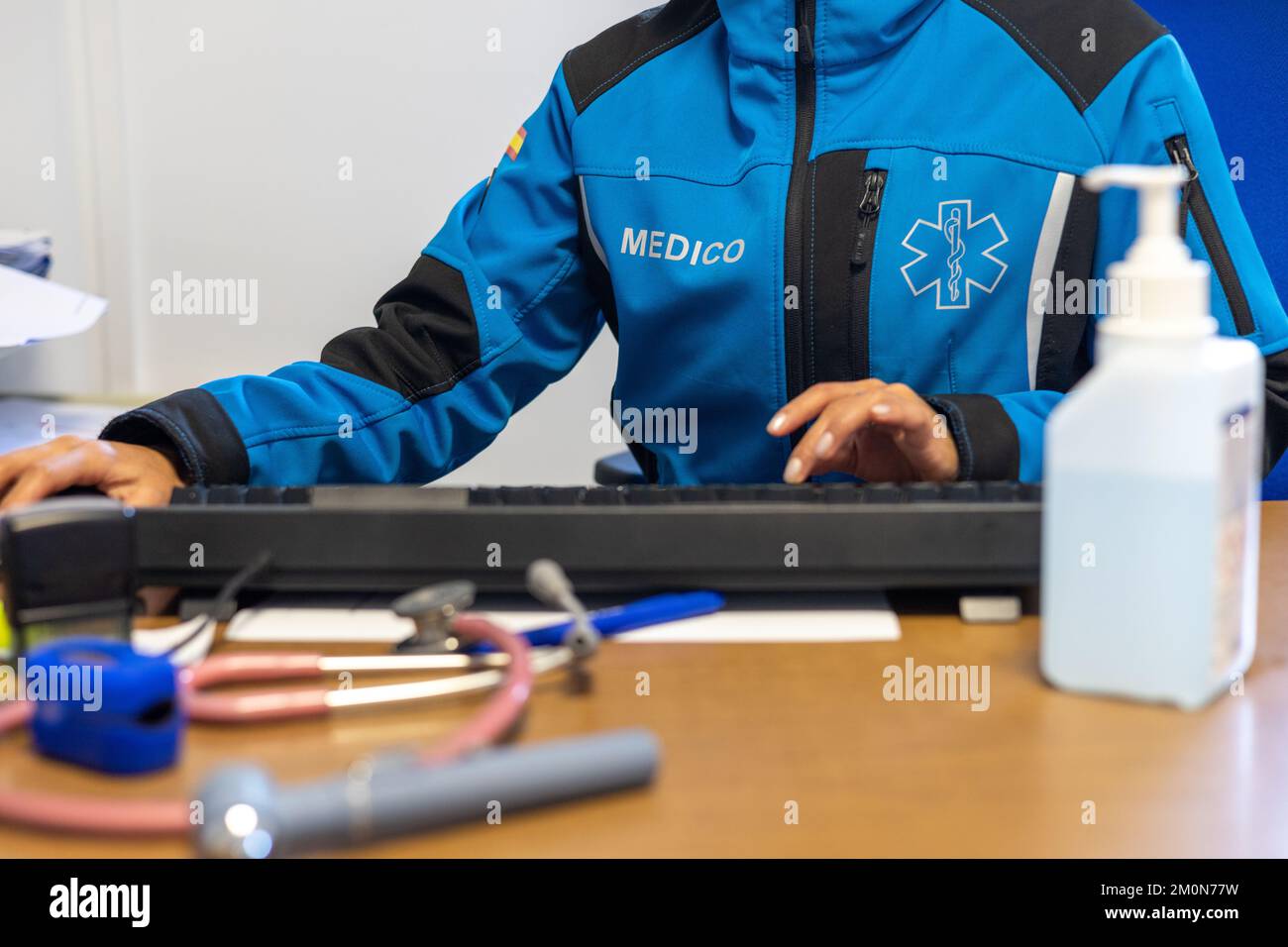 Doctor's working on laptop computer, writing prescription clipboard with record information paper folders on desk in hospital or clinic. Stock Photo