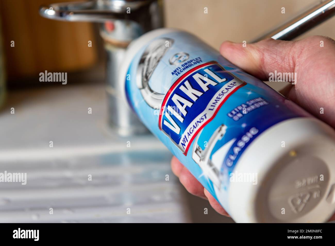 London. UK- 12.07.2022. A person applying Viakal limescale remover to a kitchen sink water tap. Stock Photo