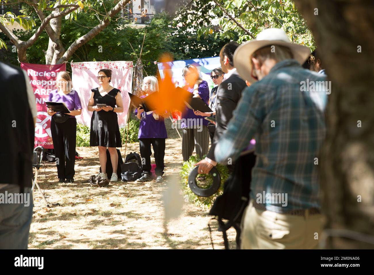 People gather near the cherry tree planted in memory of the victims of Hiroshima during a commemoration event in Tavistock Square, central London. Stock Photo