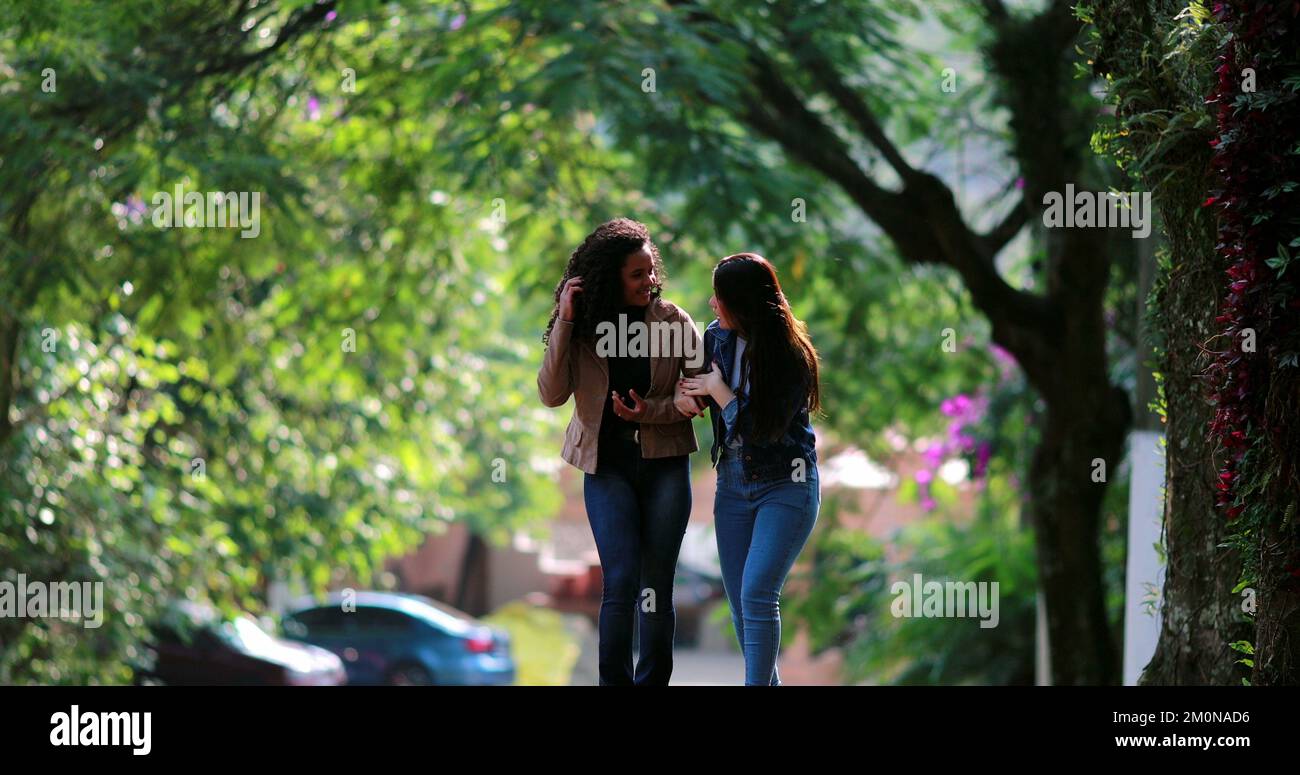 Two young women laughing together while walking in street Stock Photo ...