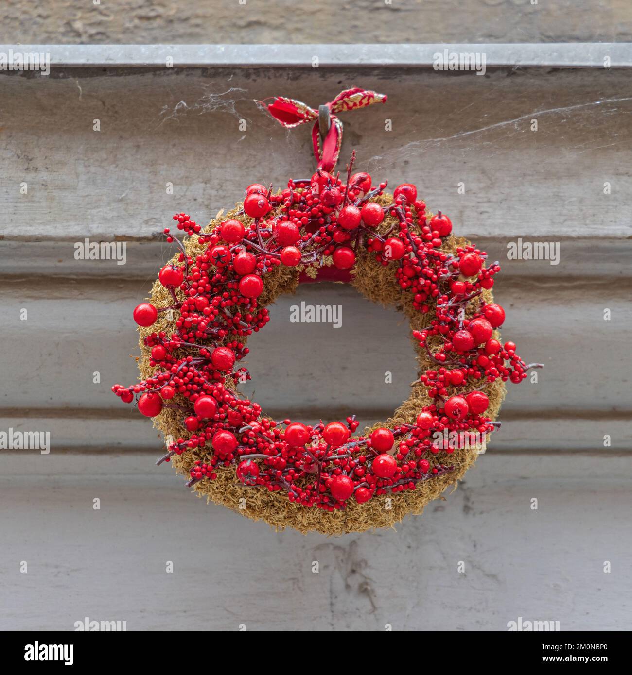 Decorative Red Berry Wreath Hanging at Building Wall Stock Photo