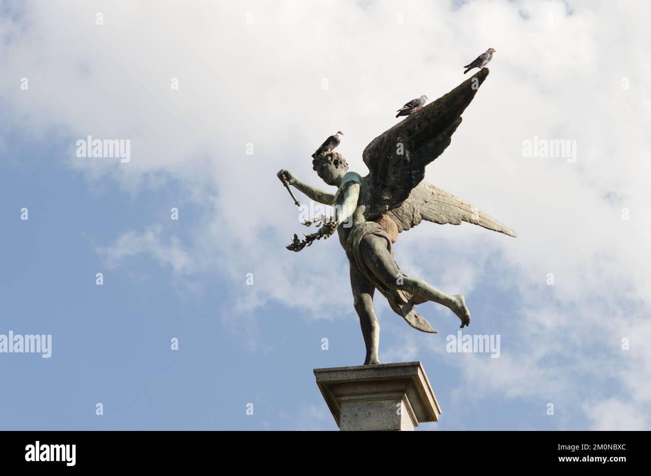 A low angle shot of beautiful statue of the Greek god Anteros under blue sky Stock Photo