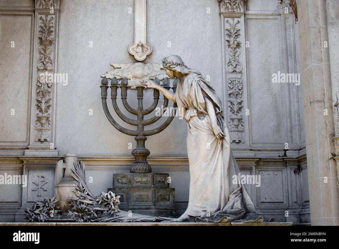 A stone statue of an angel lighting a Candelabra In Recoleta Cemetery