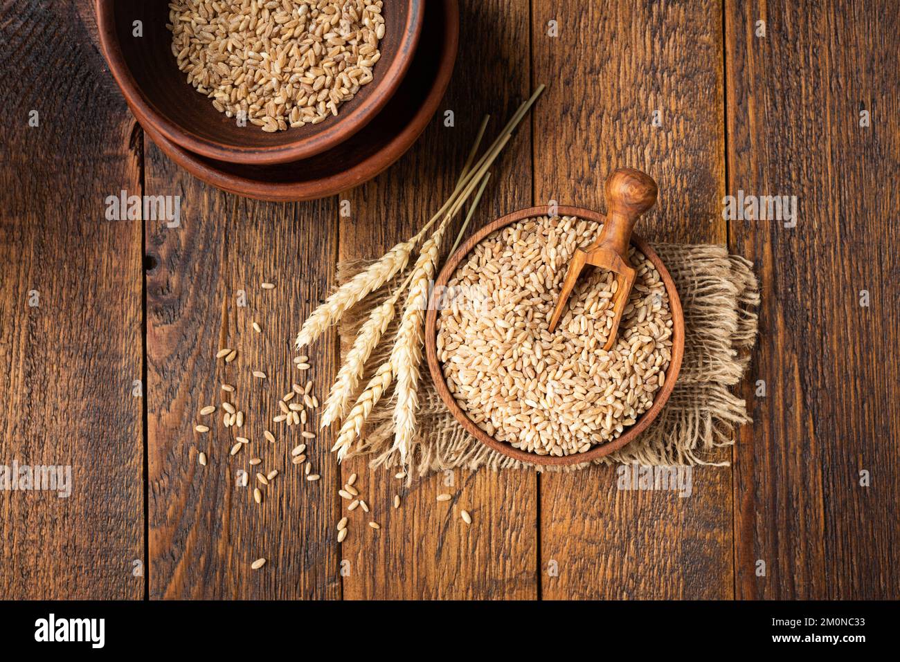 Wheat grains in bowl on a wooden table background. Concept of harvesting, agriculture, baking bread Stock Photo