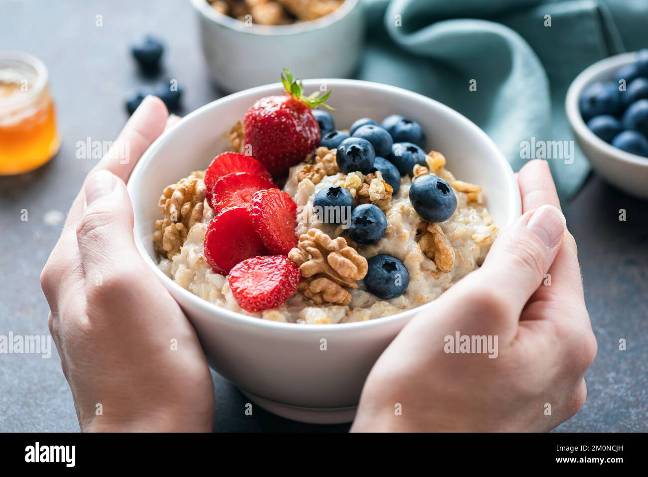 Oatmeal porridge with berries in female hands. Concept of clean eating, dieting, healthy vegan lifestyle and weight loss Stock Photo