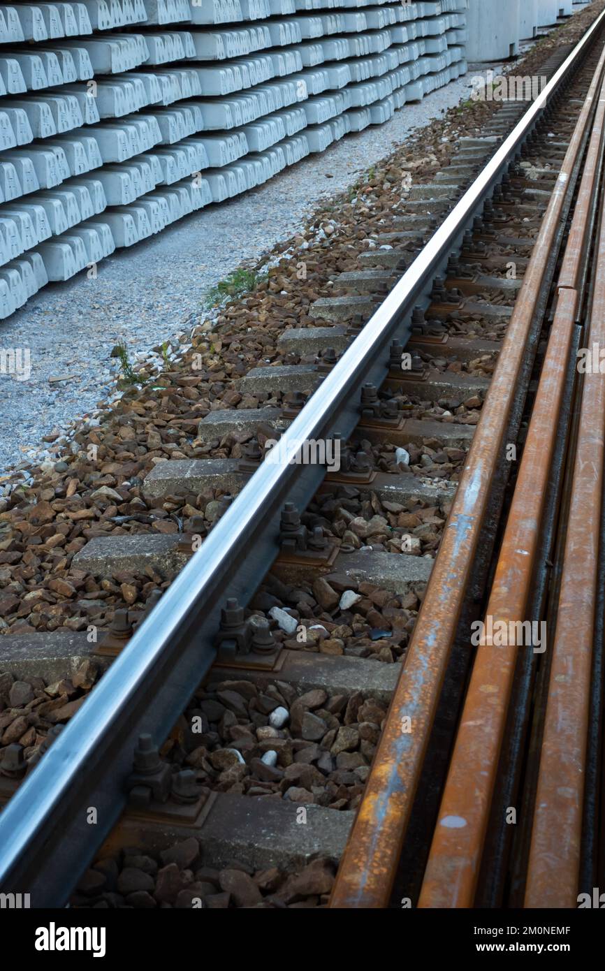 Expansion of railway lines. Train rails ready for laying and concrete sleepers arranged in even piles. Investments in rail transport as the basis for Stock Photo