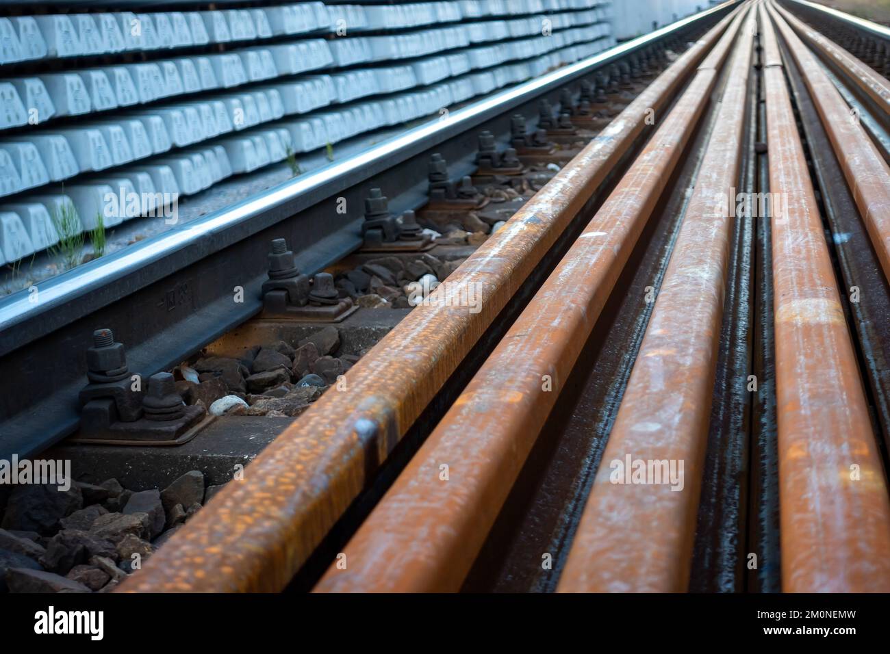 Expansion of railway lines. Train rails ready for laying and concrete sleepers arranged in even piles. Investments in rail transport as the basis for Stock Photo