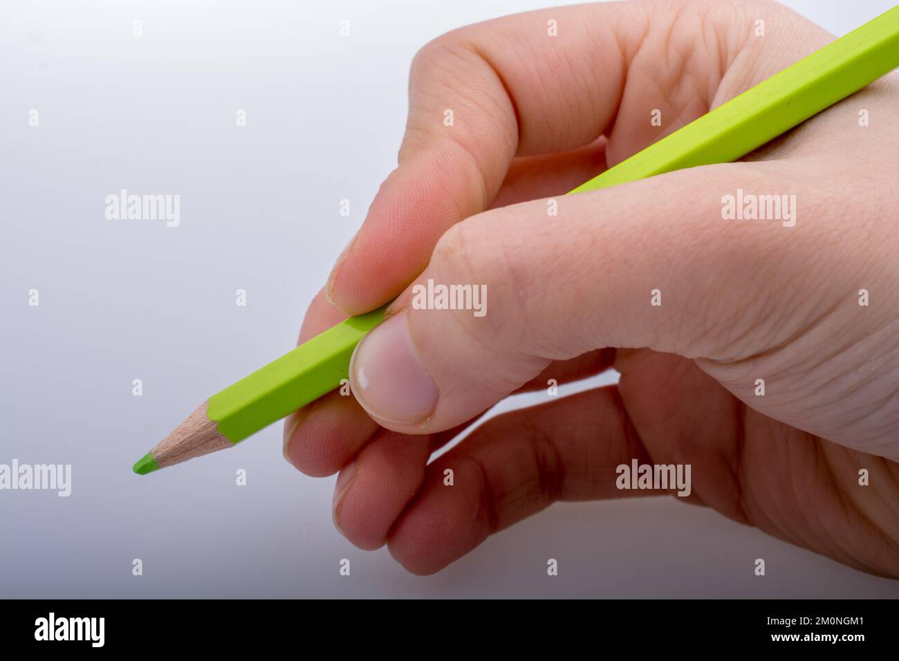 Hand holding a green color pencil on a white background Stock Photo - Alamy