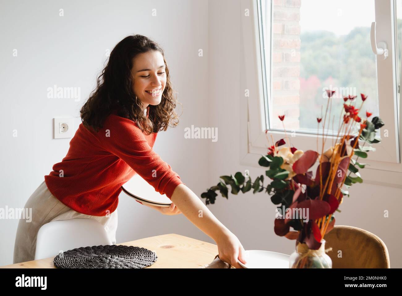 Young happy woman setting the table for dinner at home Stock Photo