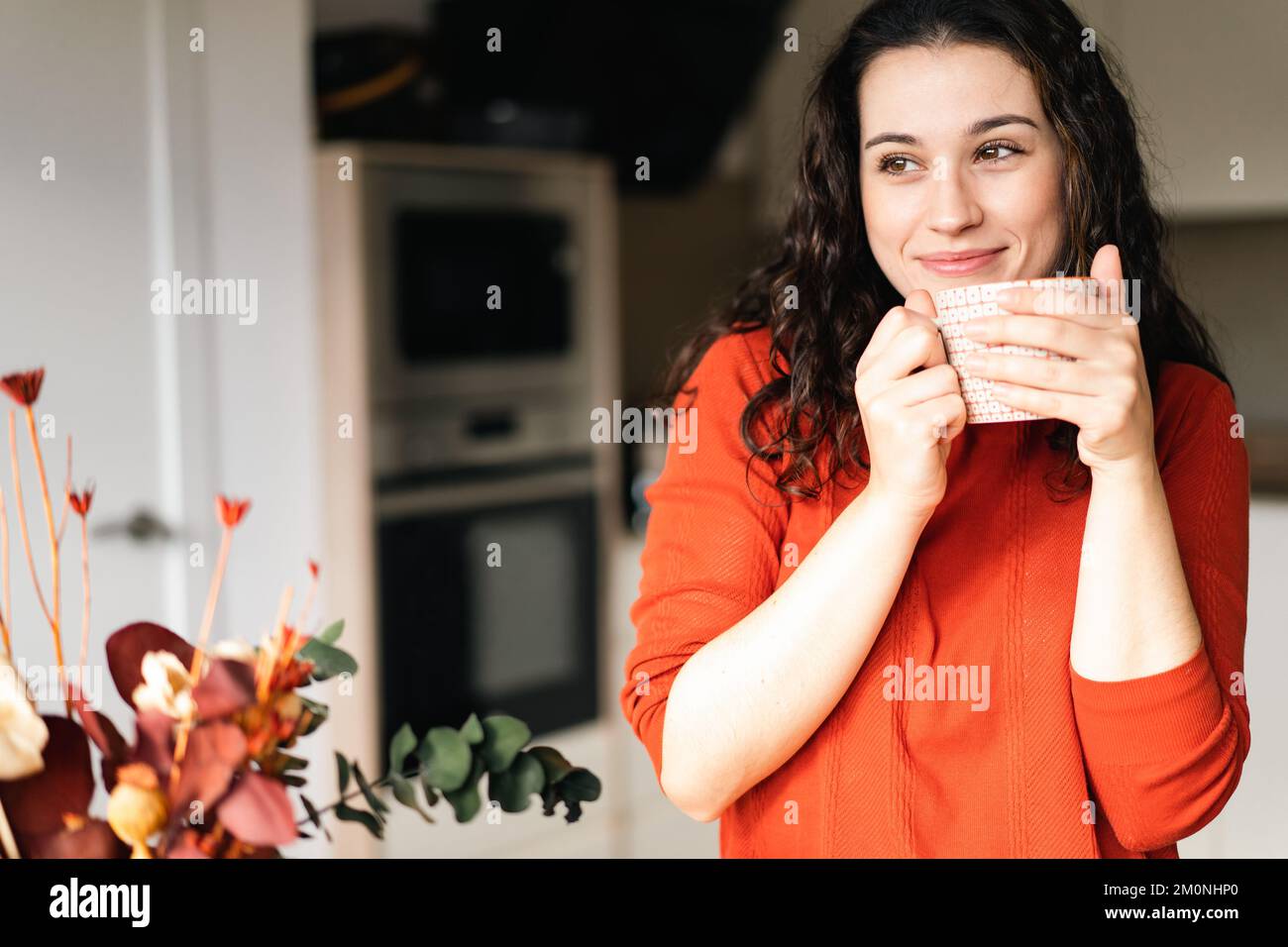 Young happy woman enjoying a hot drink in the kitchen with a dreamy look Stock Photo Alamy