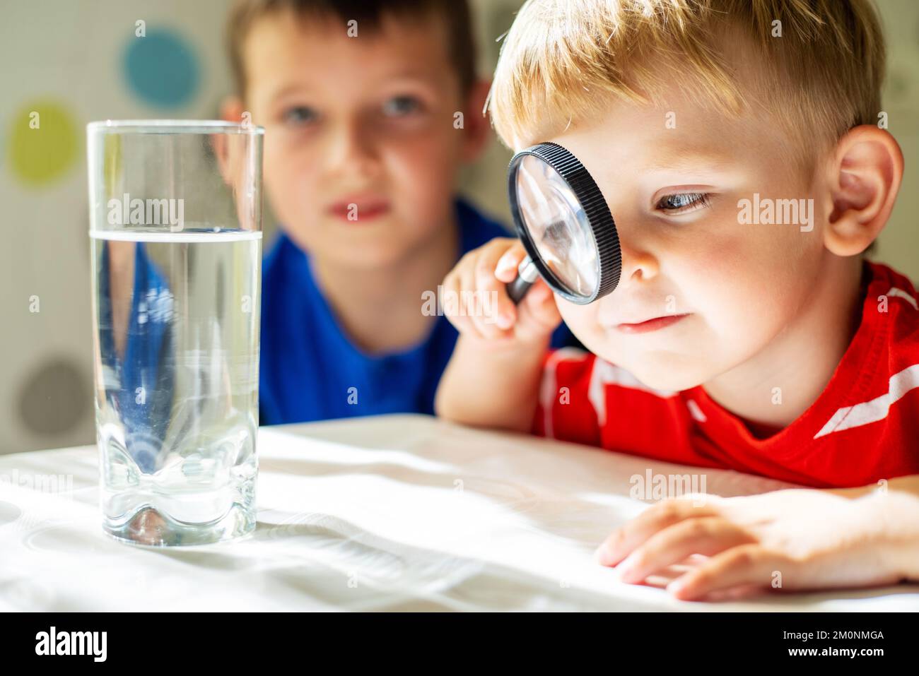 The child boy looking at water in a glass through magnifying glass