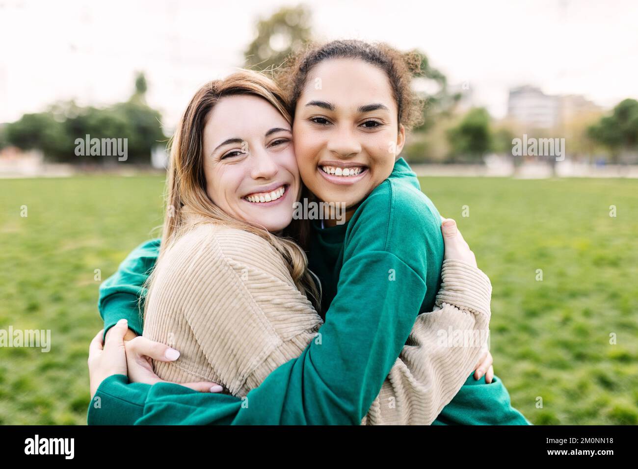 Portrait of happy young multi-ethnic female friends hugging each other outdoors Stock Photo