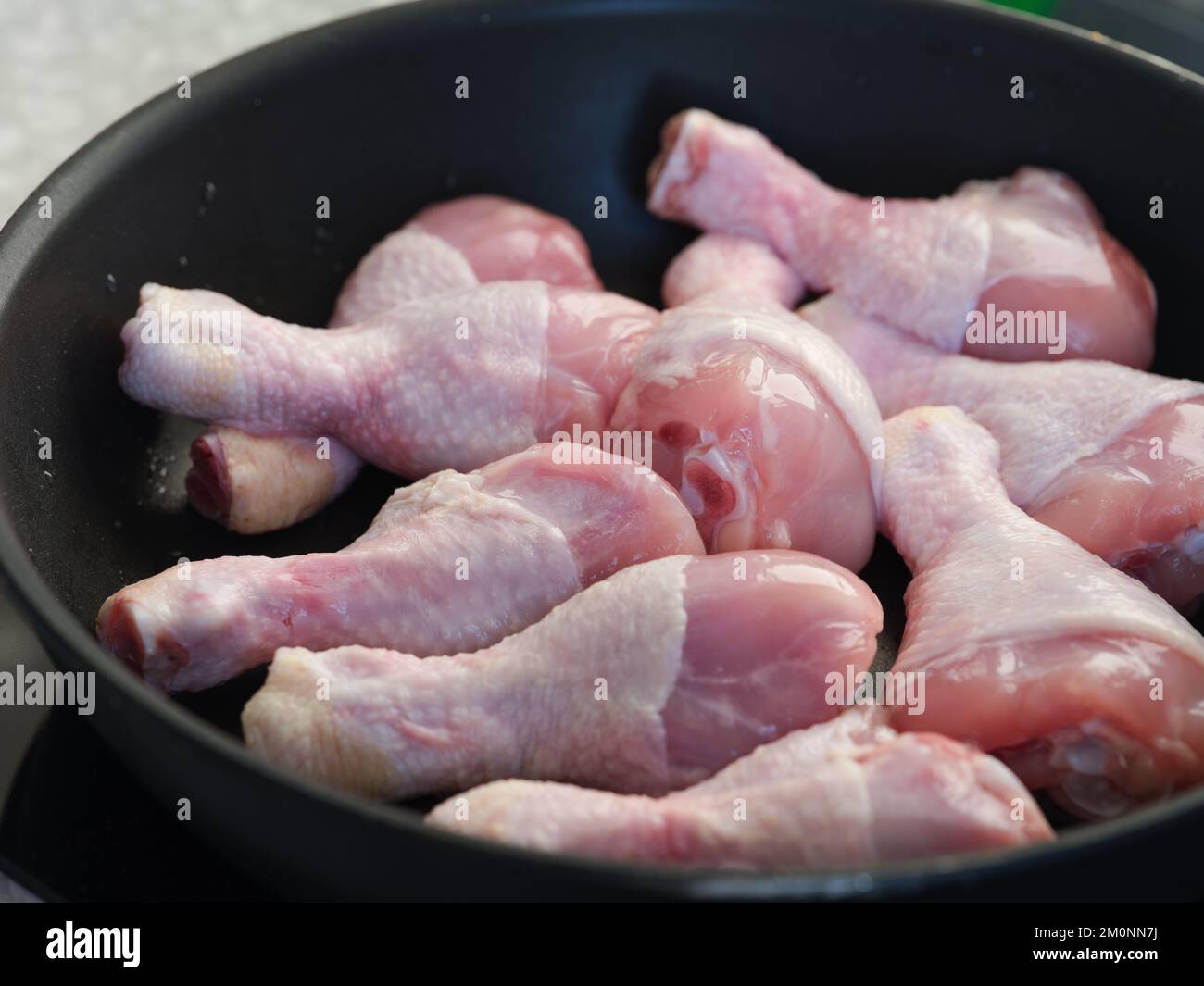 Raw chicken drumsticks in a pan being cooked. Close up. Stock Photo