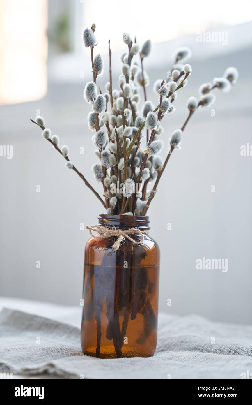 Easter decoration - a vase with willow branches on the table in a dark brown glass vase. Palm Sunday concept with copy space. High quality photo Stock Photo