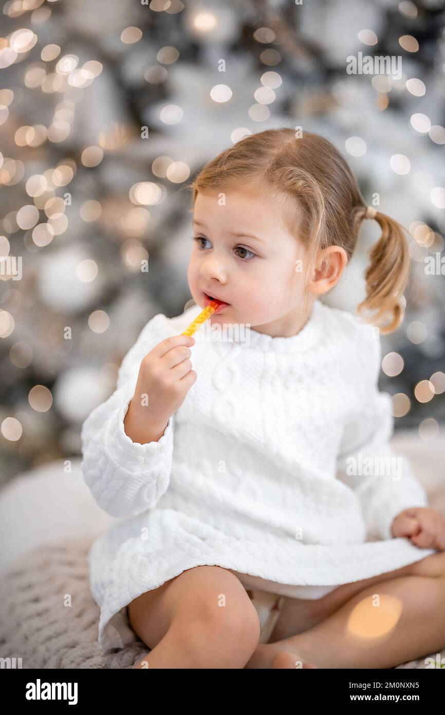 Very nice charming little girl blonde in white dress sitting on a child ...
