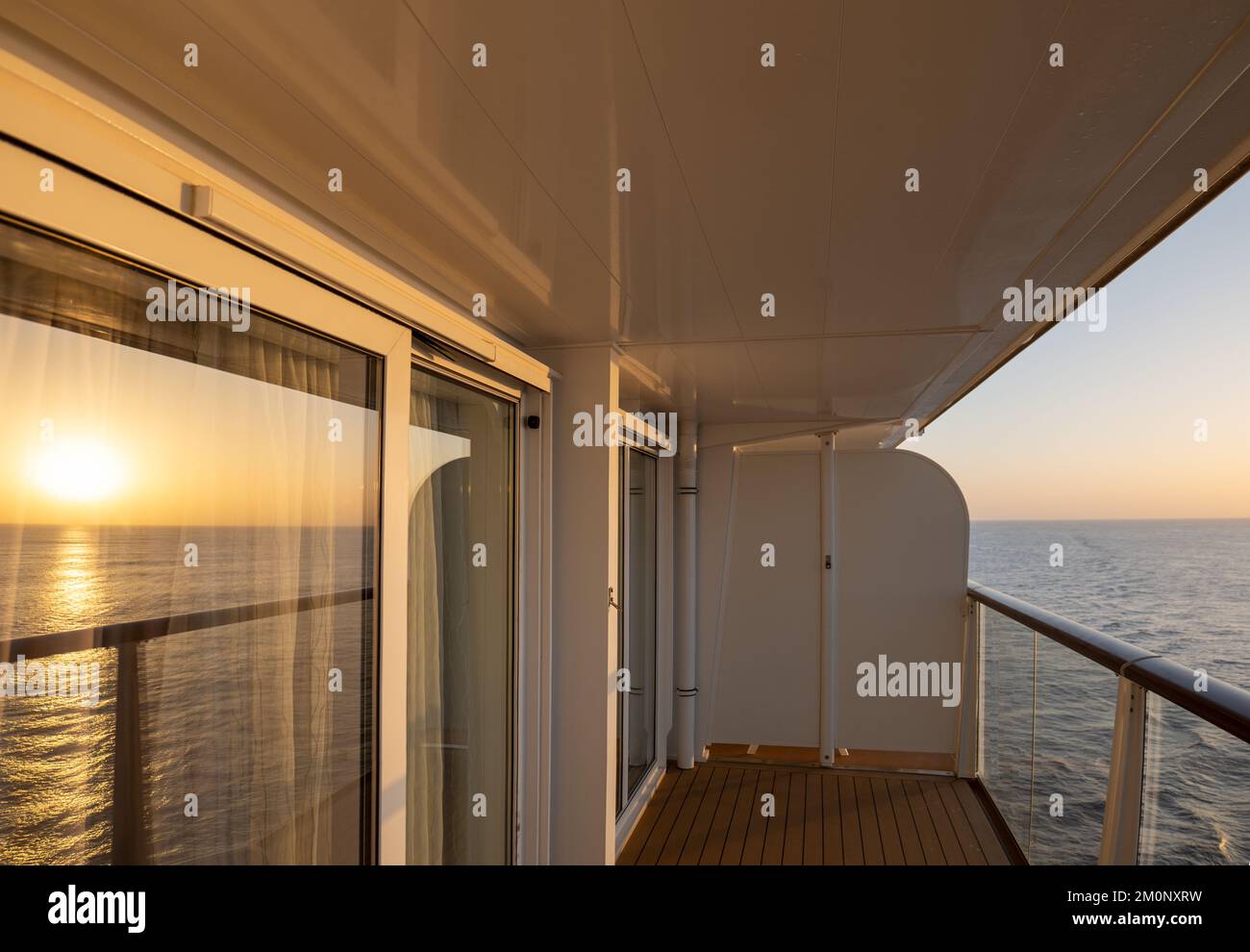 Reflecting sunrise on glass door of an outside cabin of a cruise ship. Stock Photo