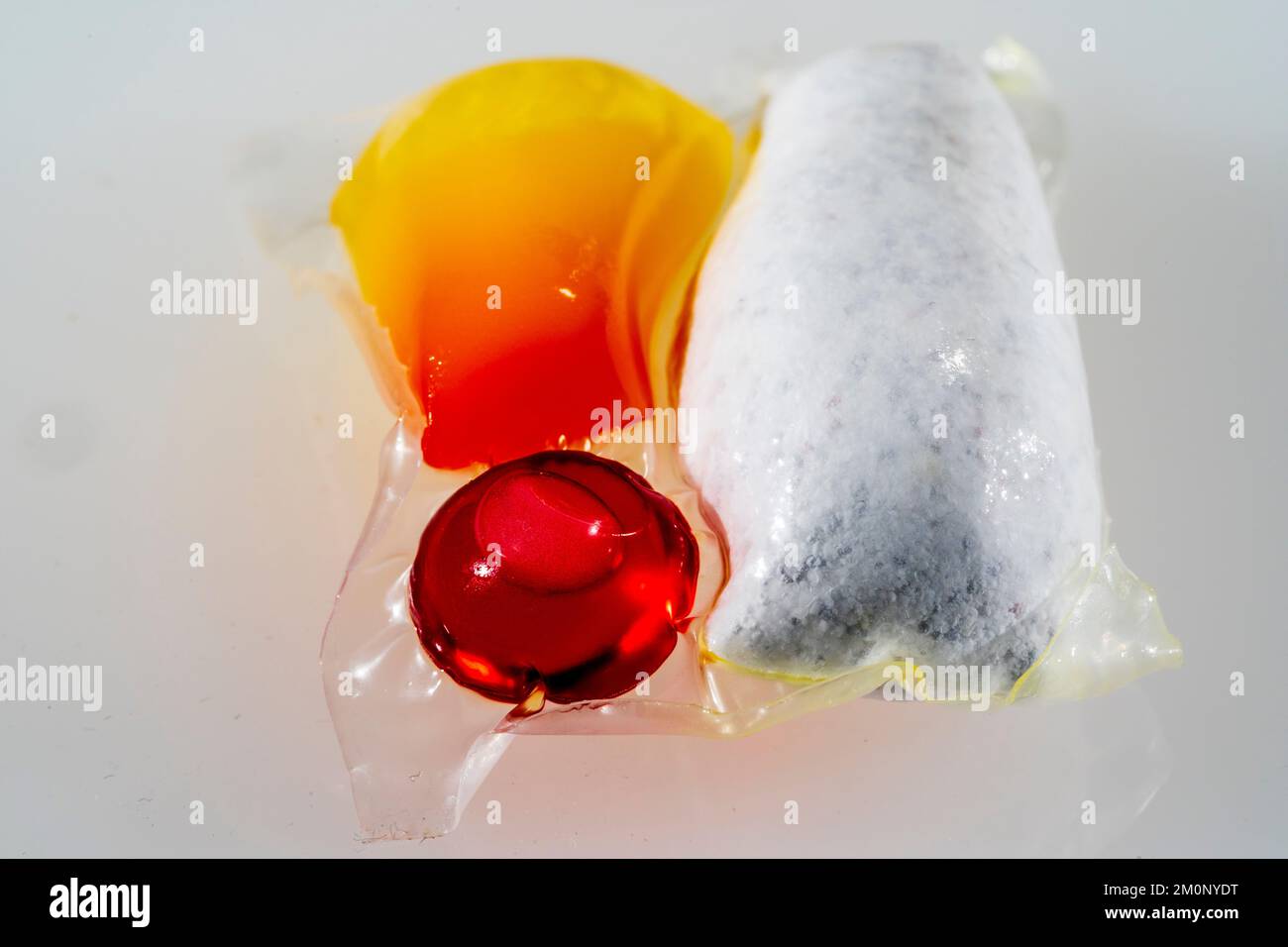 https://c8.alamy.com/comp/2M0NYDT/dishwasher-tablet-close-up-of-a-single-household-dishwasher-tablet-with-three-capsules-one-red-one-orange-and-one-of-white-detergent-powder-2M0NYDT.jpg