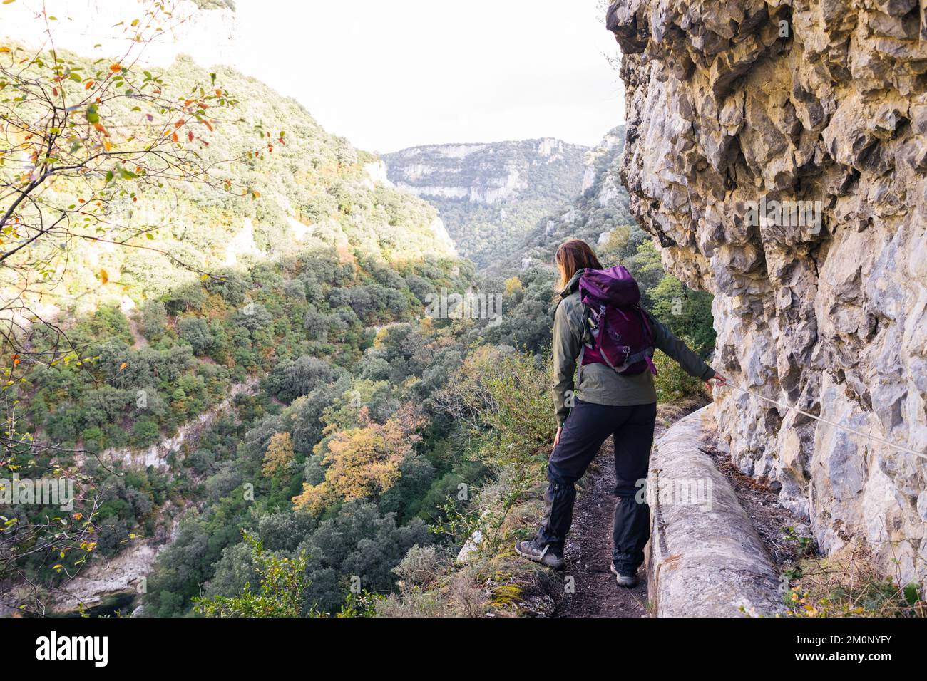 Trekker woman looking the precipice in a high canyon. Stock Photo