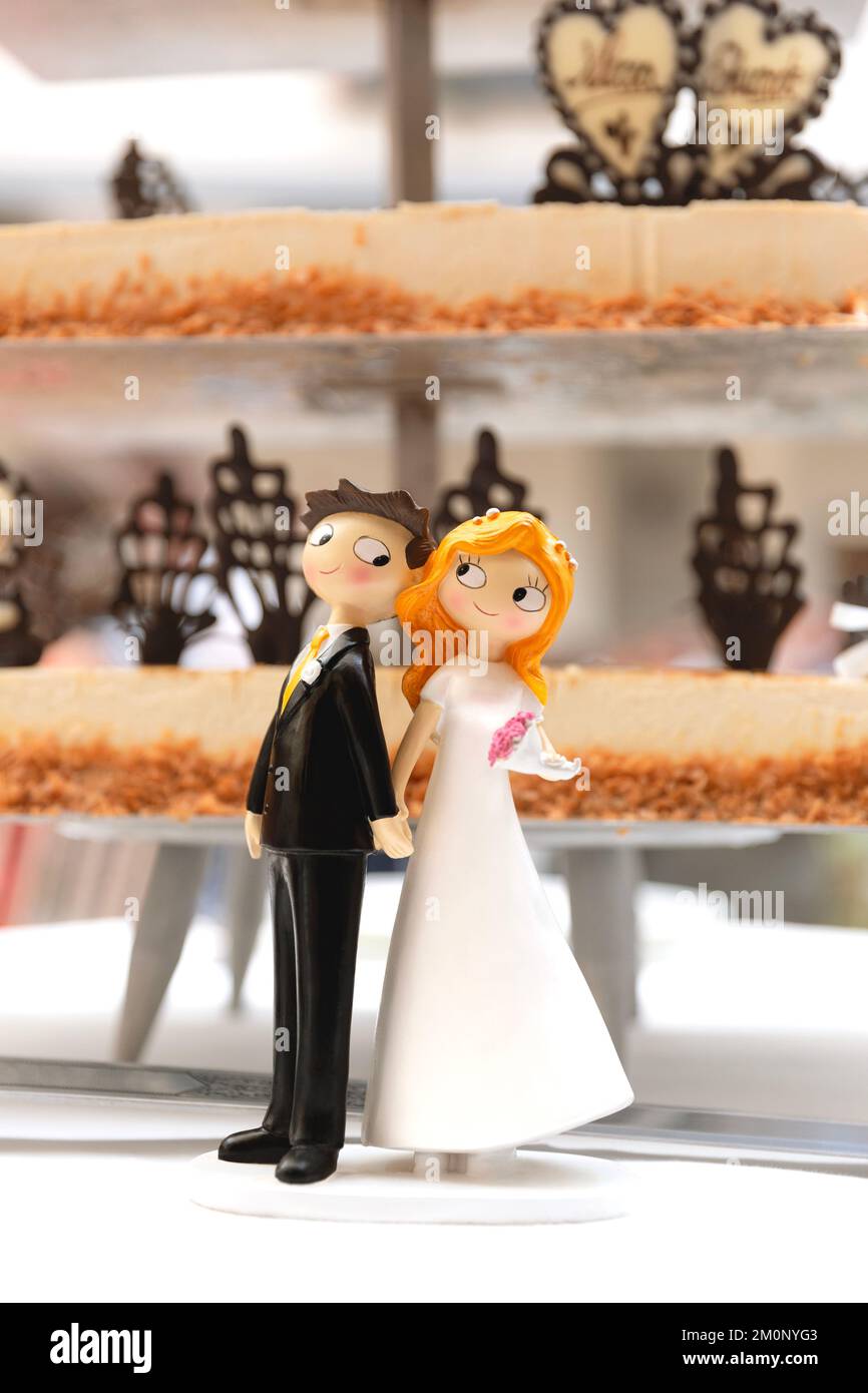 Detail of bride and groom figures next to wedding cake. Concept of marriage bond. Stock Photo