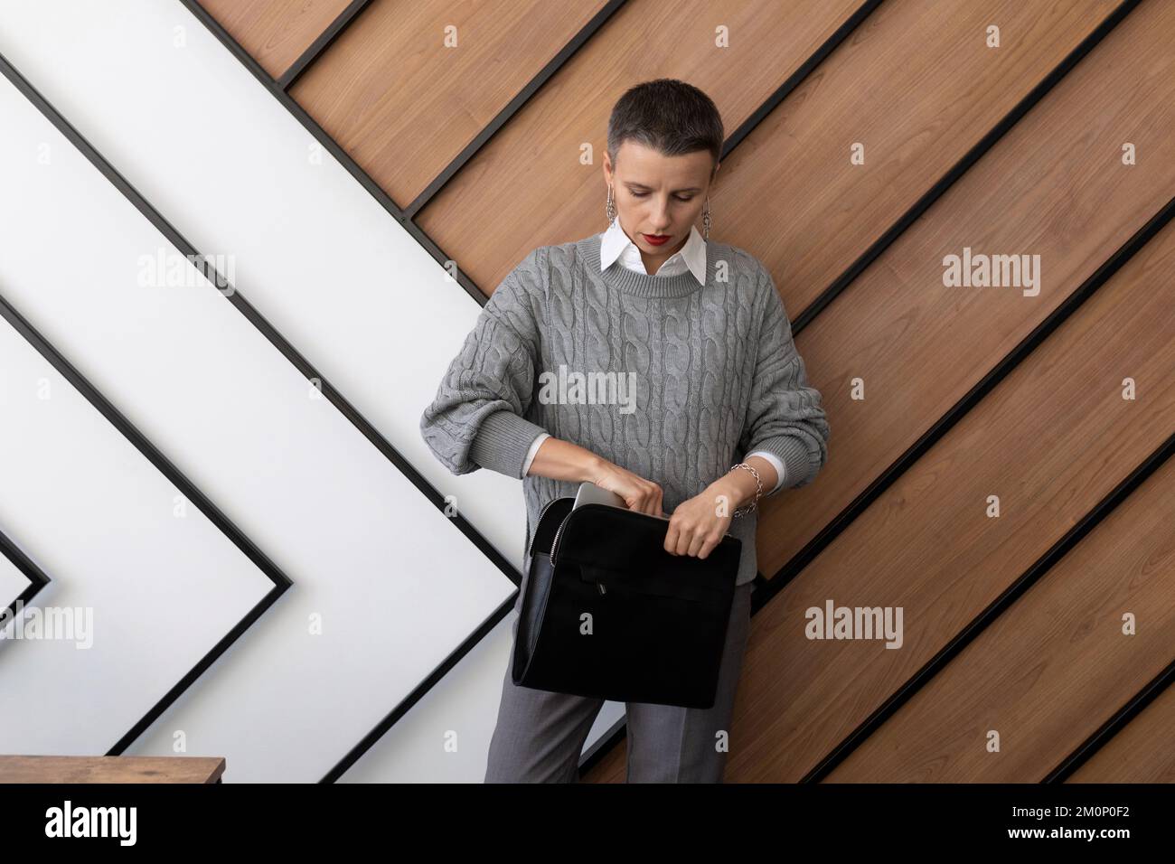 office worker a woman with a short haircut stands against the wall a ...