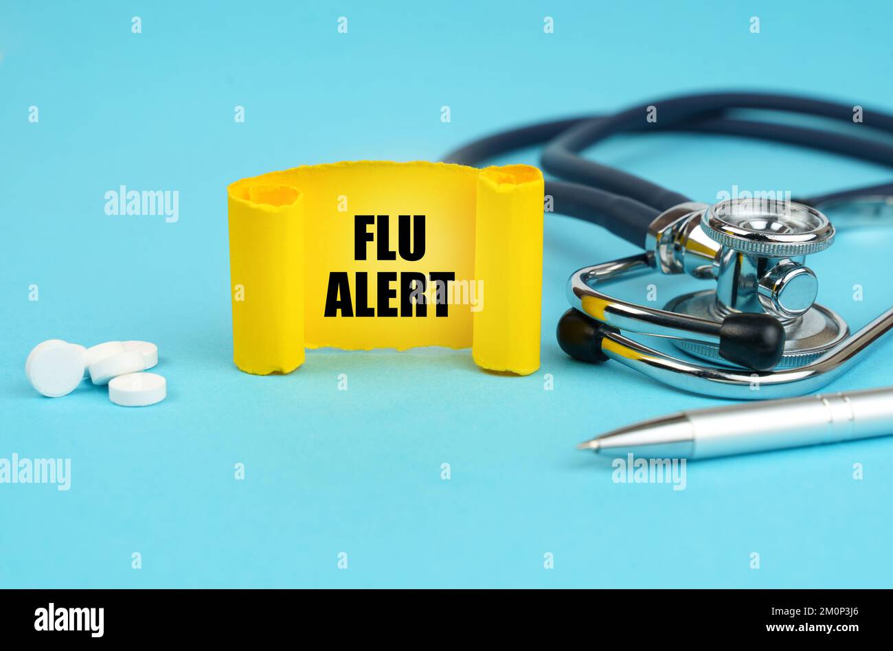 Medical concept. On a blue surface, a stethoscope, pills, a pen and a yellow sign with the inscription - Flu alert Stock Photo