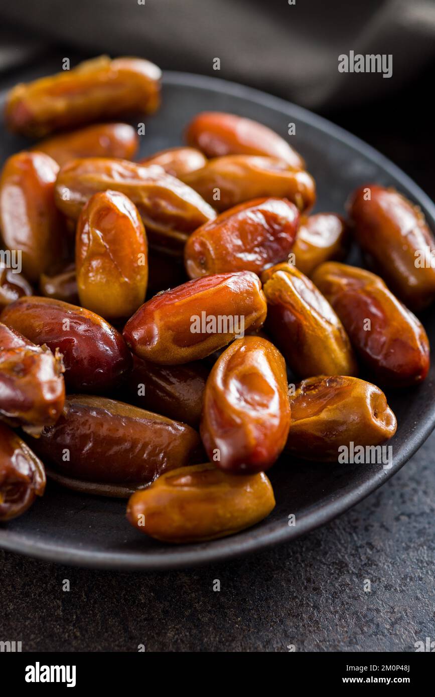 Dried dates fruit on plate on the black table. Stock Photo