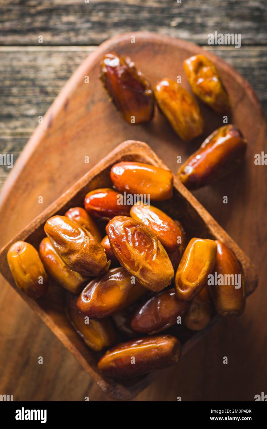Dried dates fruit in the wooden bowl. Top view Stock Photo - Alamy