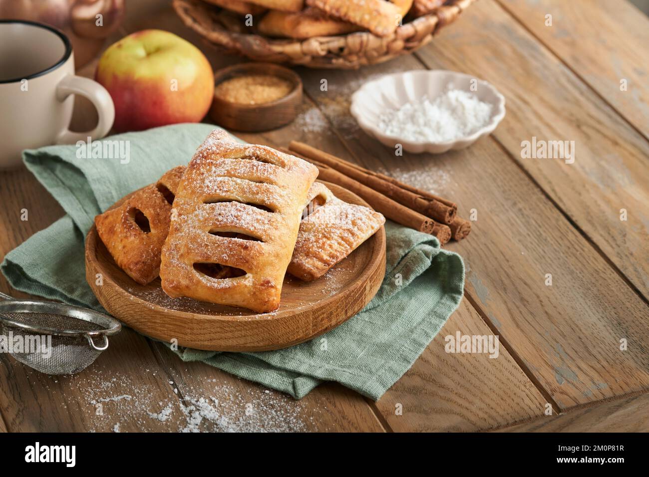 Hand pies. Mini puff pastry or hand pies stuffed with apple and sprinkle sugar powder in wooden plate. Homemade pie snack with crust for breakfast rus Stock Photo