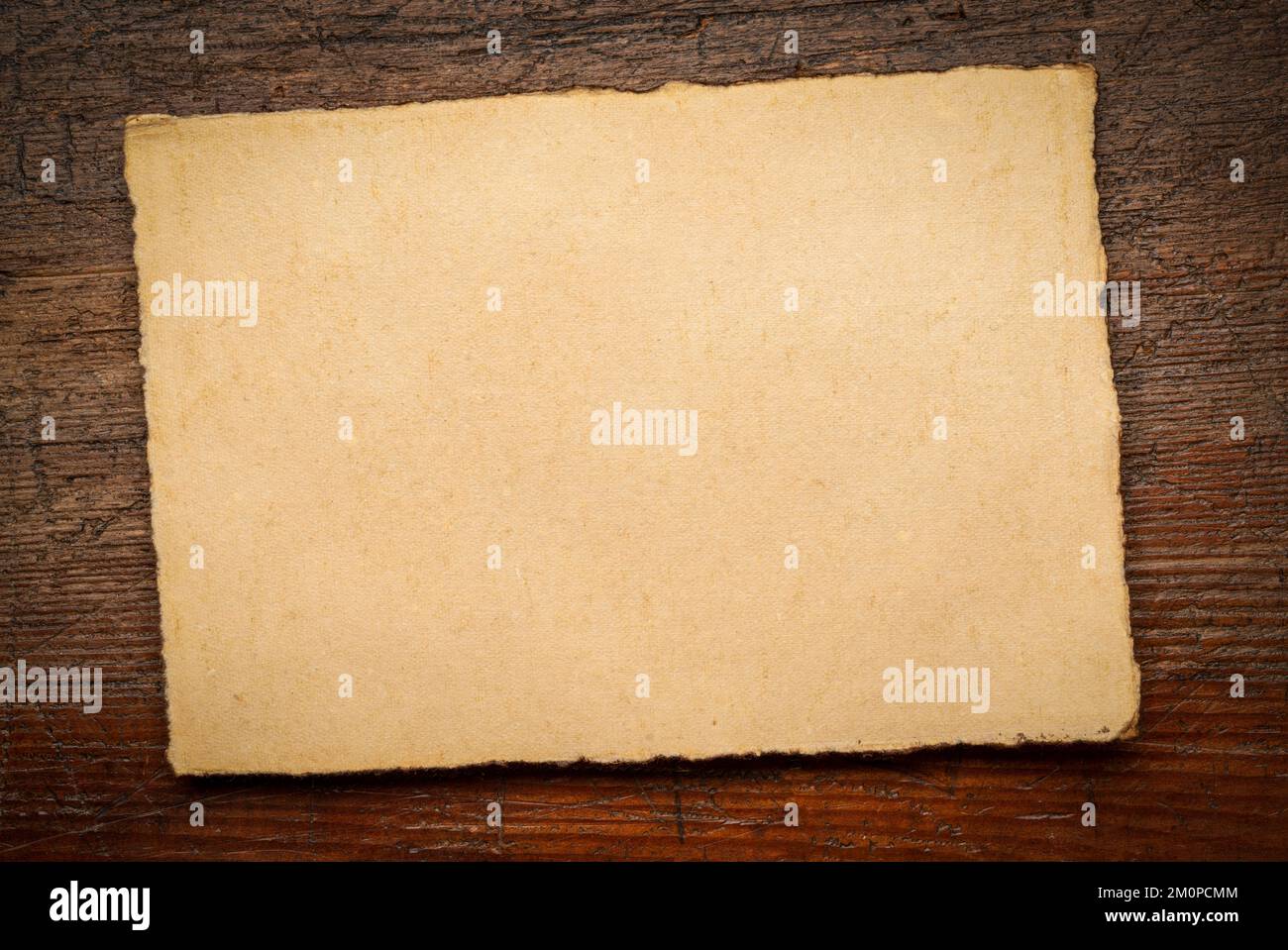 sheet of blank handmade paper with rough edges against rustic weathered ...