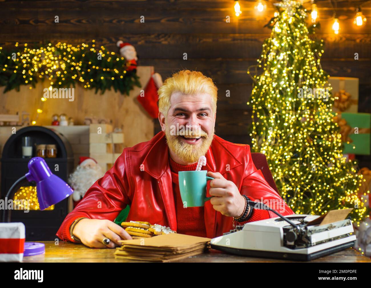 Smiling man in red leather jacket with mug of milk and cookie. Merry Christmas. New year background. Stock Photo