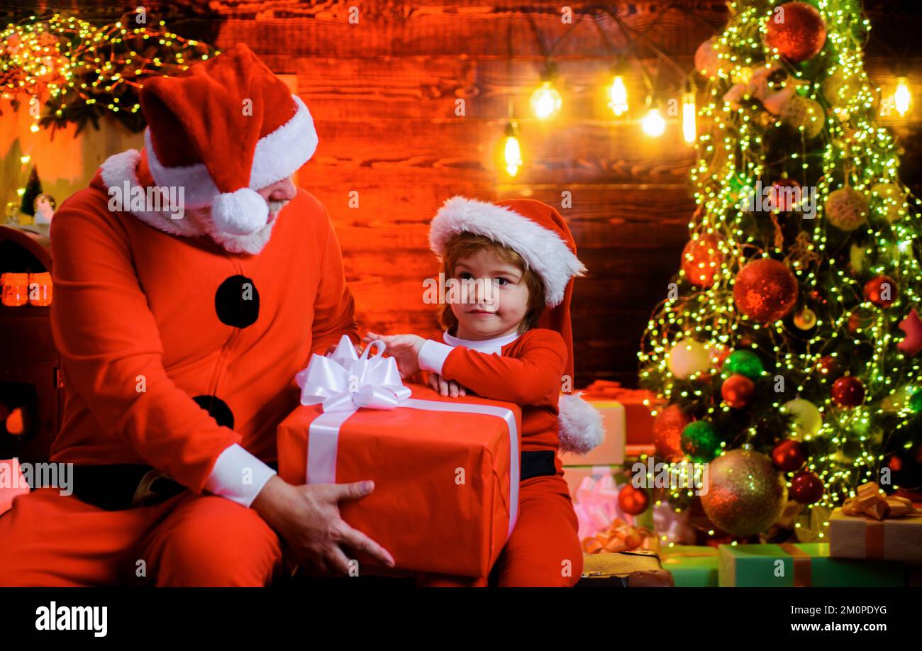 Christmas gift. Santa Claus and little child with present at home. Family holiday. Happy new year. Stock Photo
