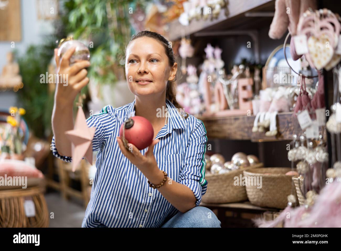 Cheerful lady in casual shirt buying Christmas bulbs before holidays in a store Stock Photo