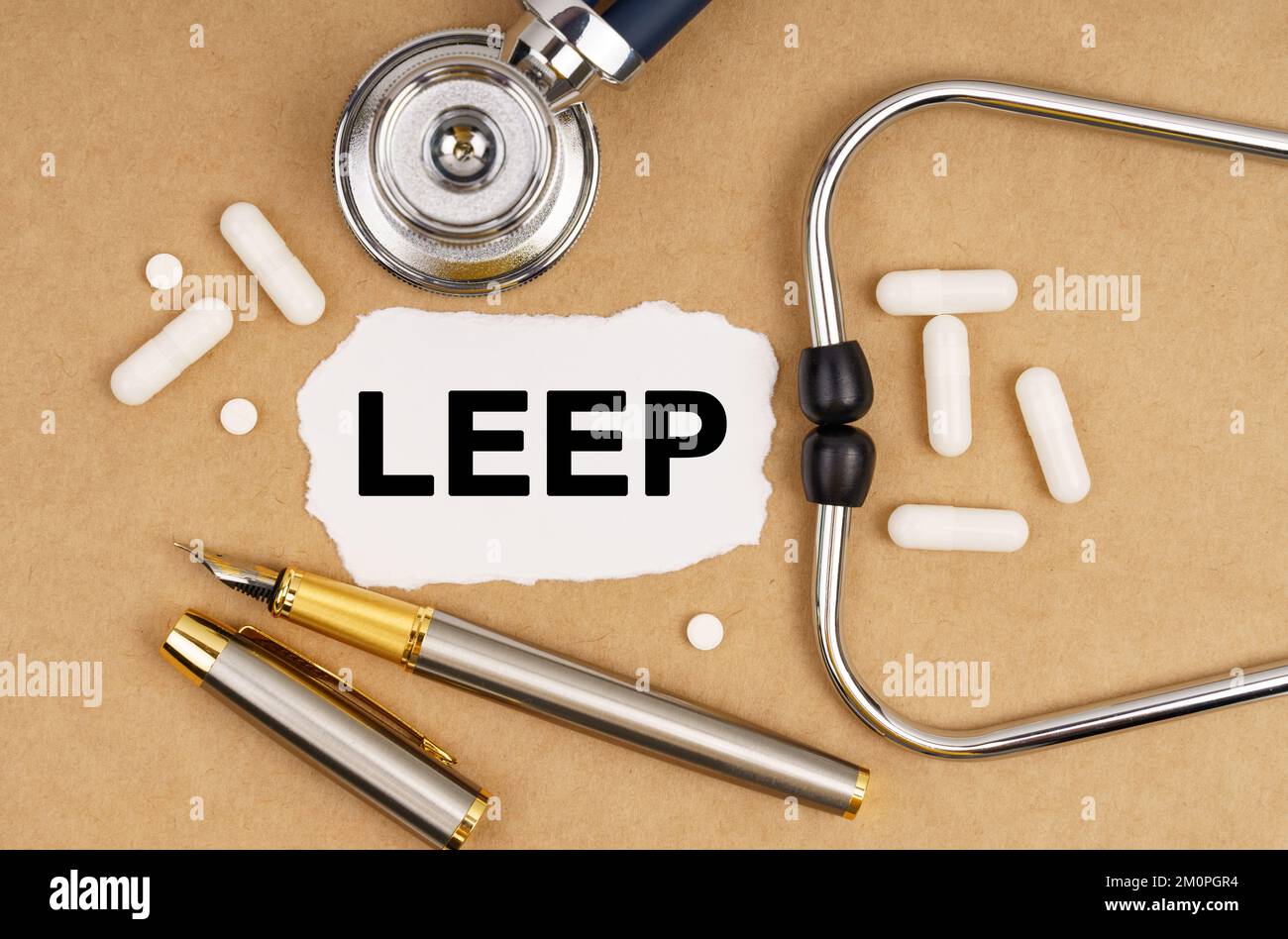 Medicine and health concept. On the table is a stethoscope, pills, a pen and paper with the inscription - LEEP Stock Photo