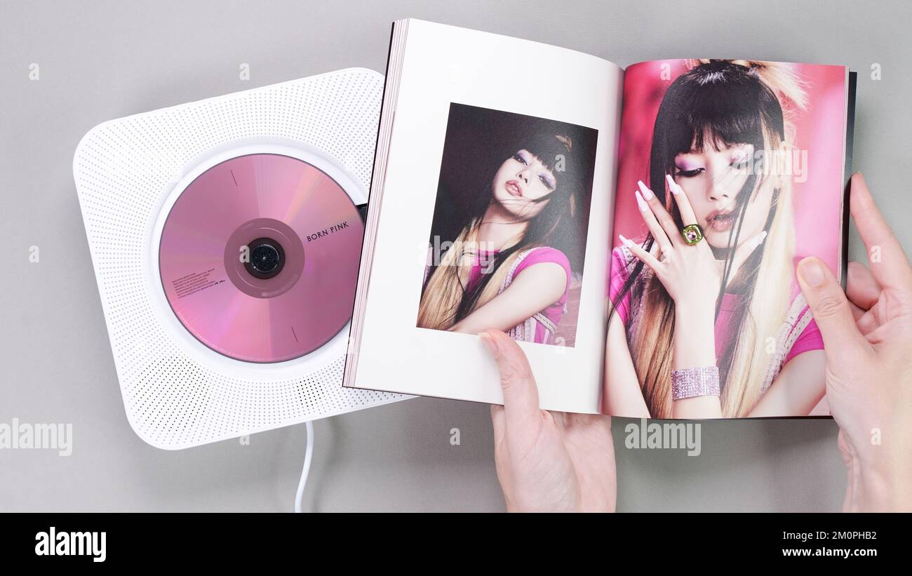 Fan hands holding BlackPink BORN PINK 2nd Album photobook with Lisa on grey. Pink music CD in player. South Korean girl group BlackPink. Space for tex Stock Photo