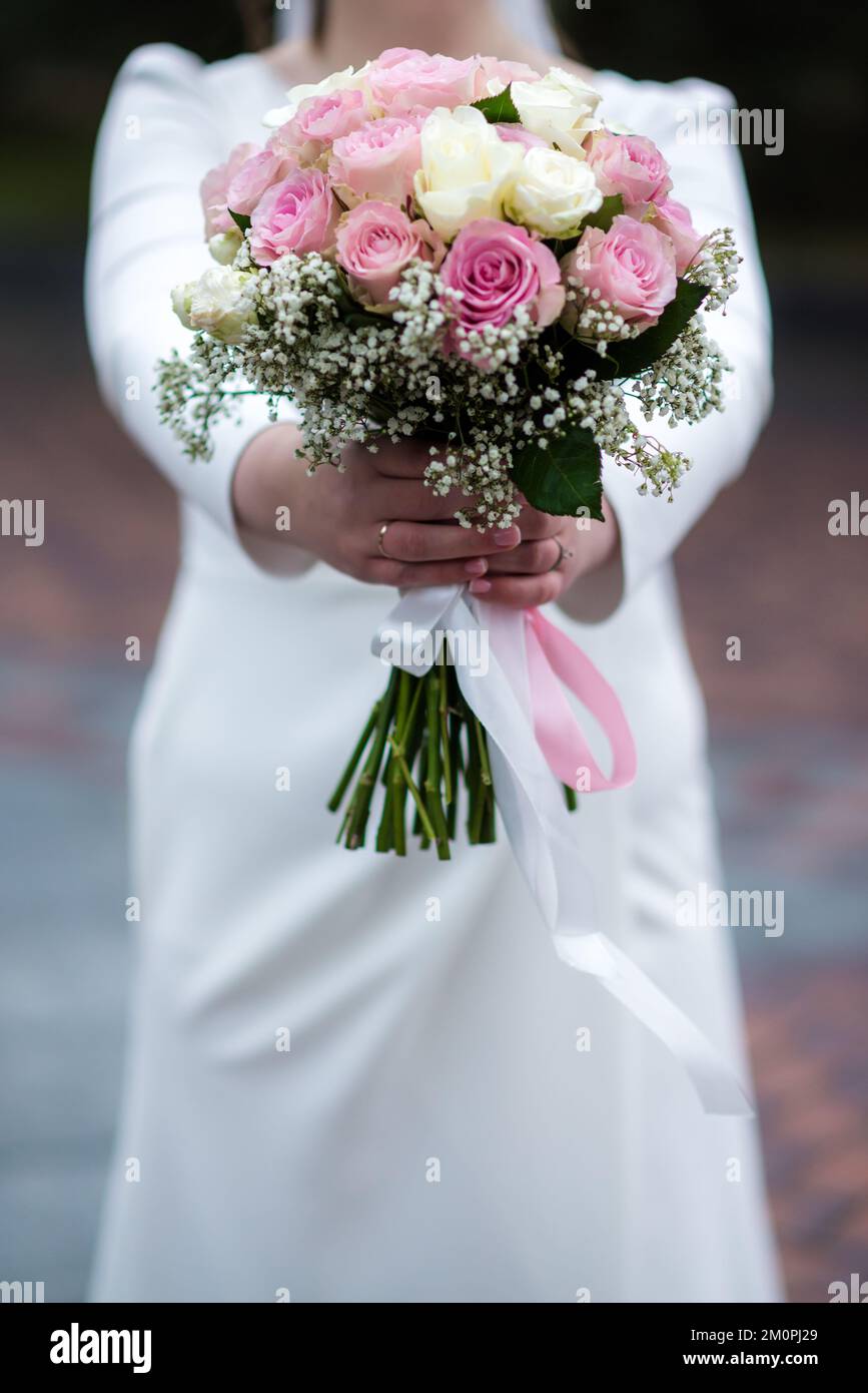 The bride in a white wedding dress is holding a bouquet of white ...