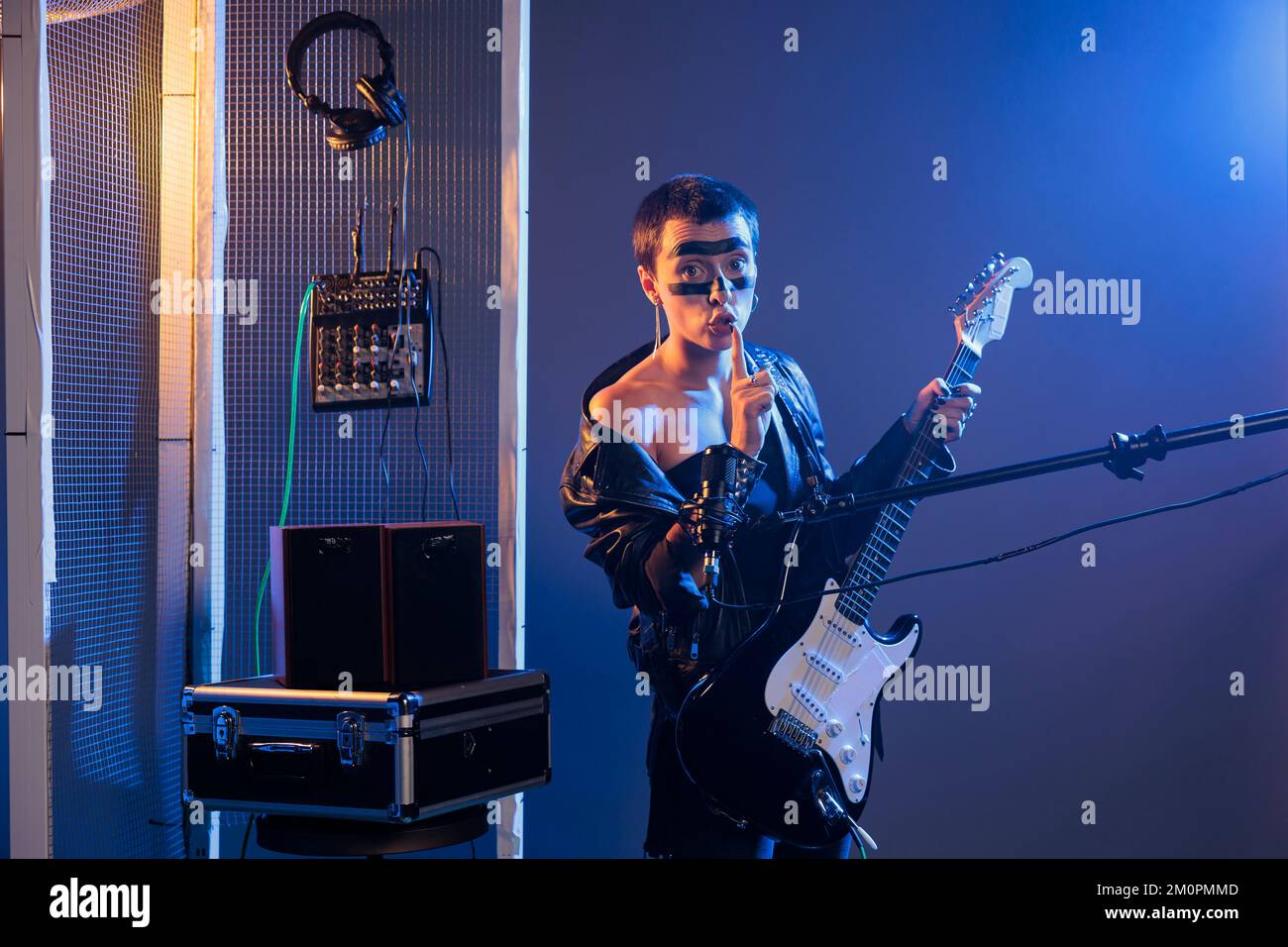 Musical performer doing hush mute sign, playing guitar at microphone and  showing secret privacy gesture. Heavy metal singer keeping silence and  secrecy, confidential symbol in studio Stock Photo - Alamy