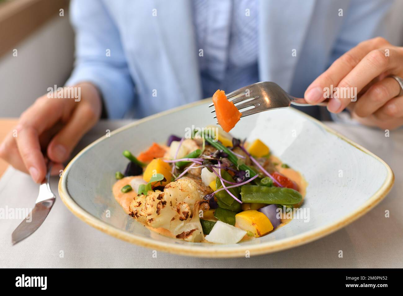 A woman eating fish with vegetables in a restaurant Stock Photo - Alamy