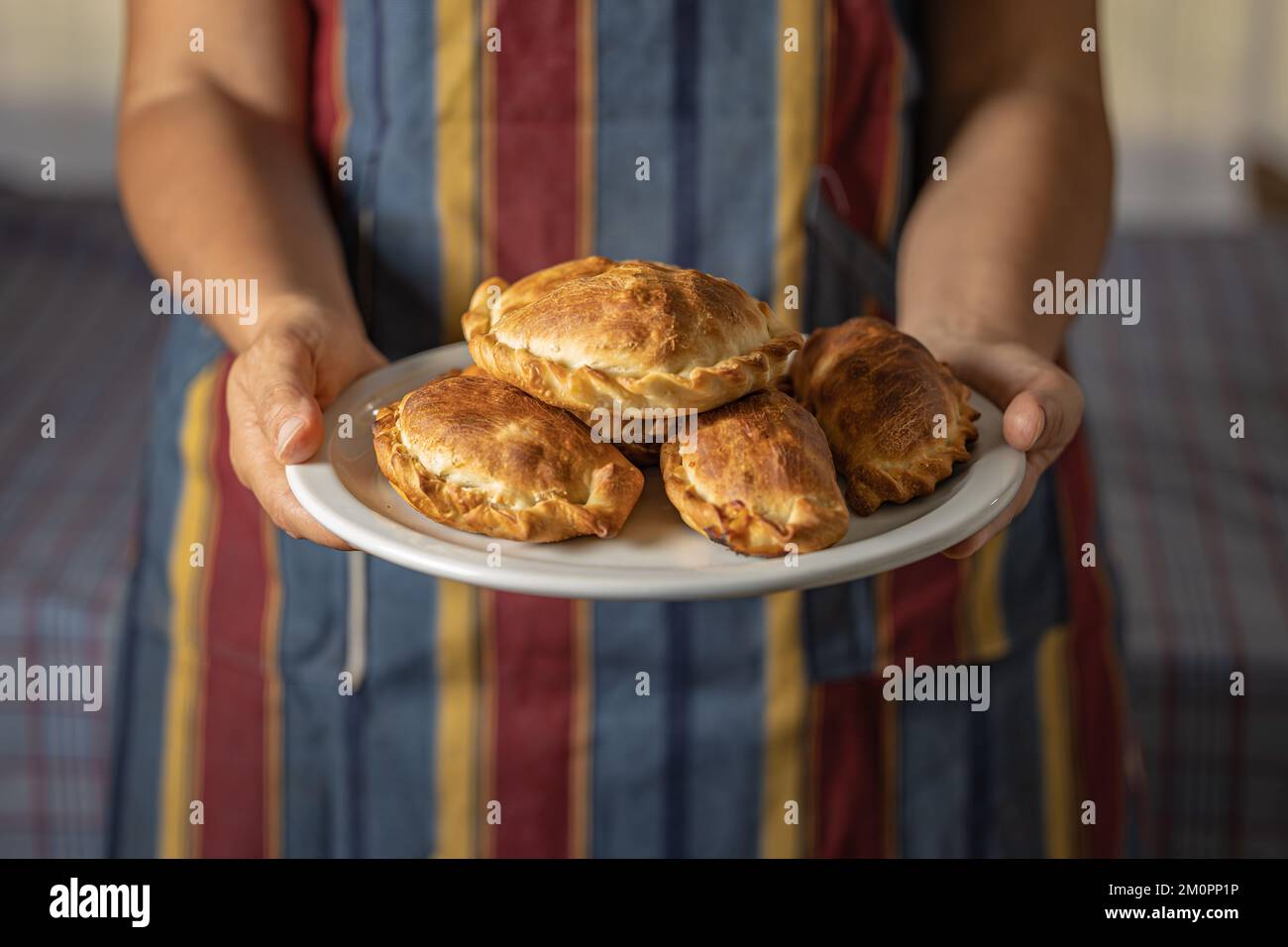 Woman in apron holding a tray with Argentine empanadas. Stock Photo