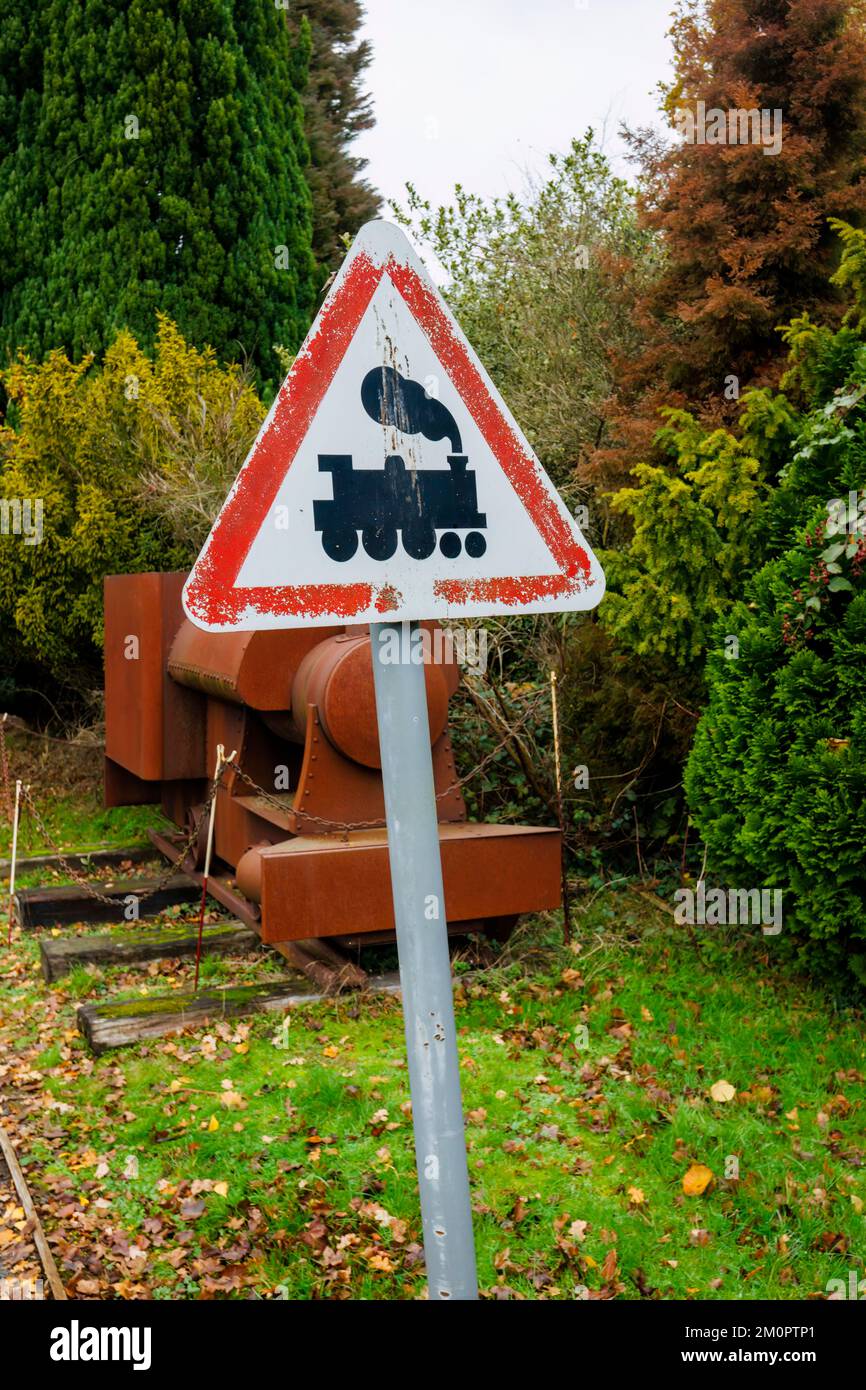 A vintage white with red border triangular railway crossing sign with a warning picture of a train at Mizens Railway in Knaphill, Woking, Surrey Stock Photo