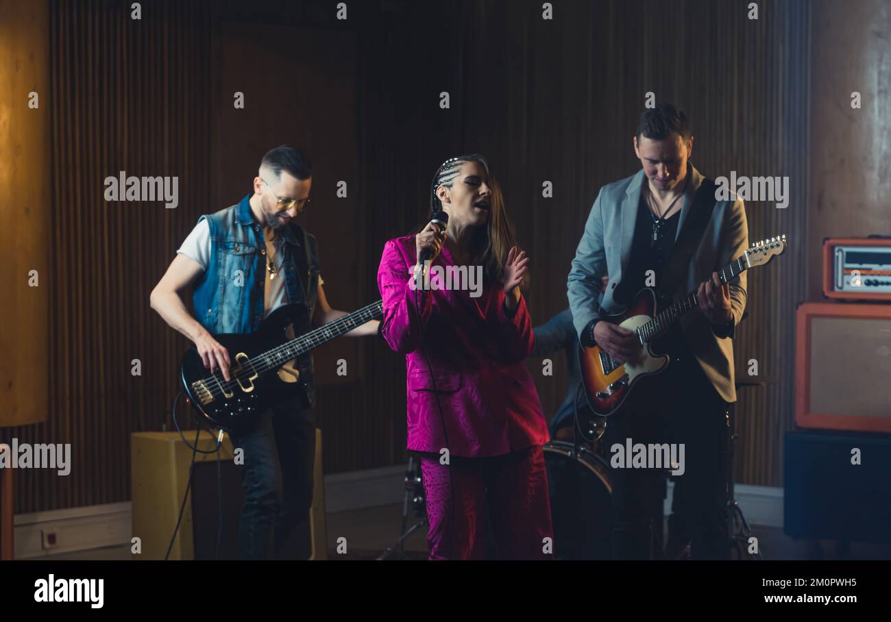 Woman solo singing with the musicians accompanying her on the guitars. High quality photo Stock Photo
