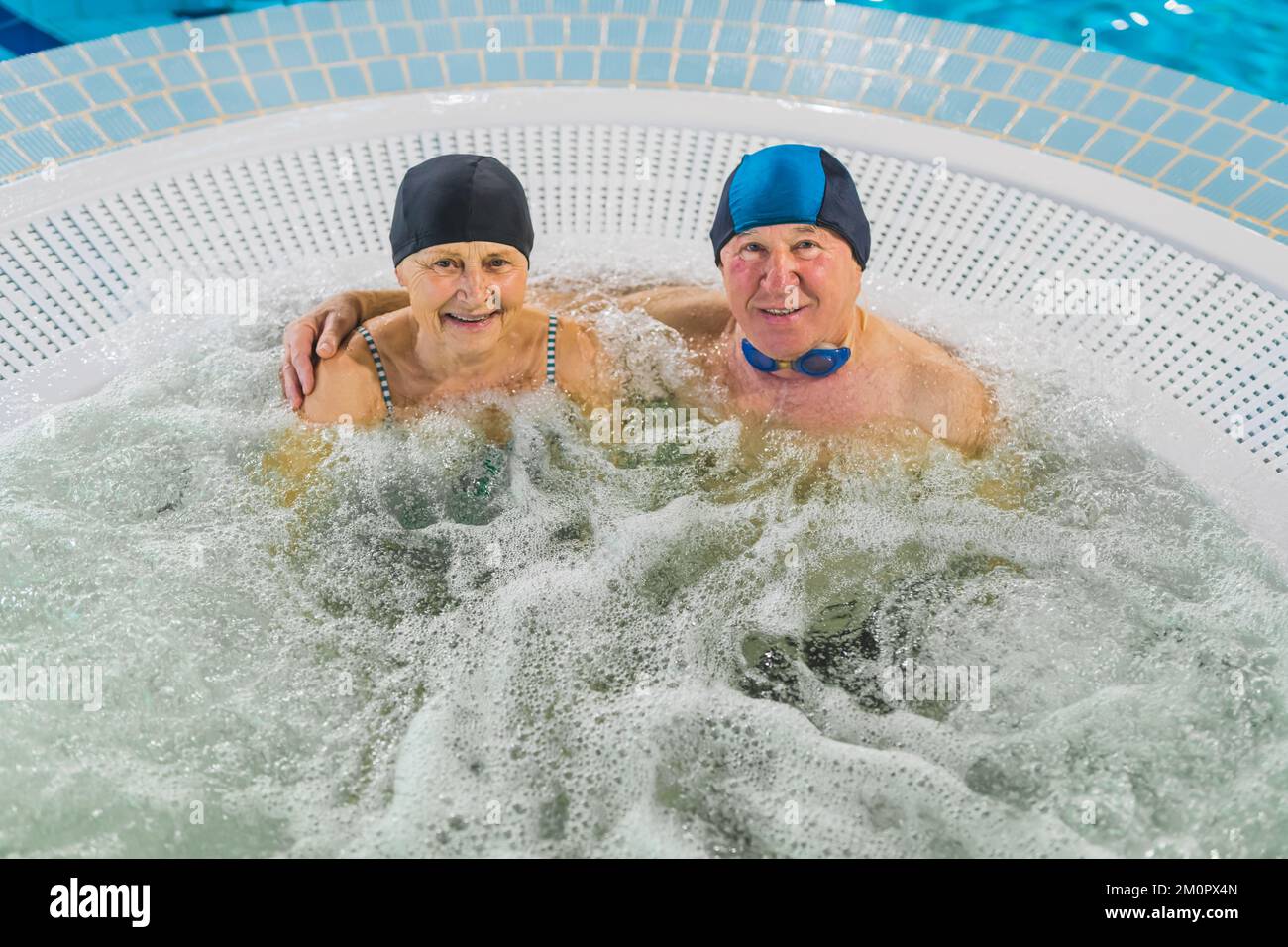 Adorable happy caucasian married senior couple relaxing in a Jacuzzi. Swimming equipment: caps, glasses and swim suits. High quality photo Stock Photo