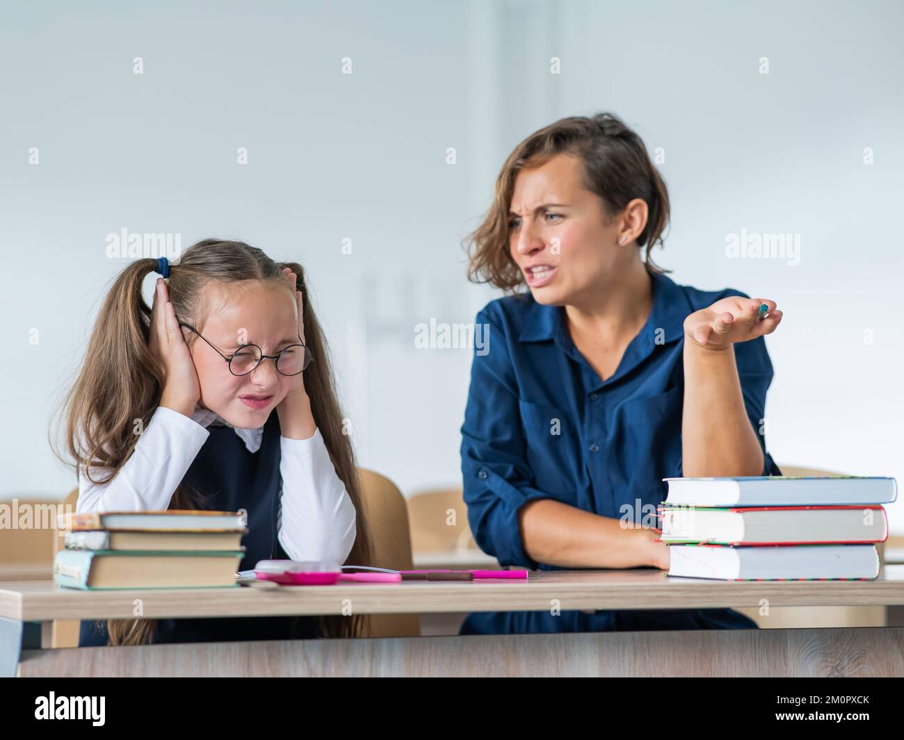 A female teacher yells at a student. Little girl covers her ears with
