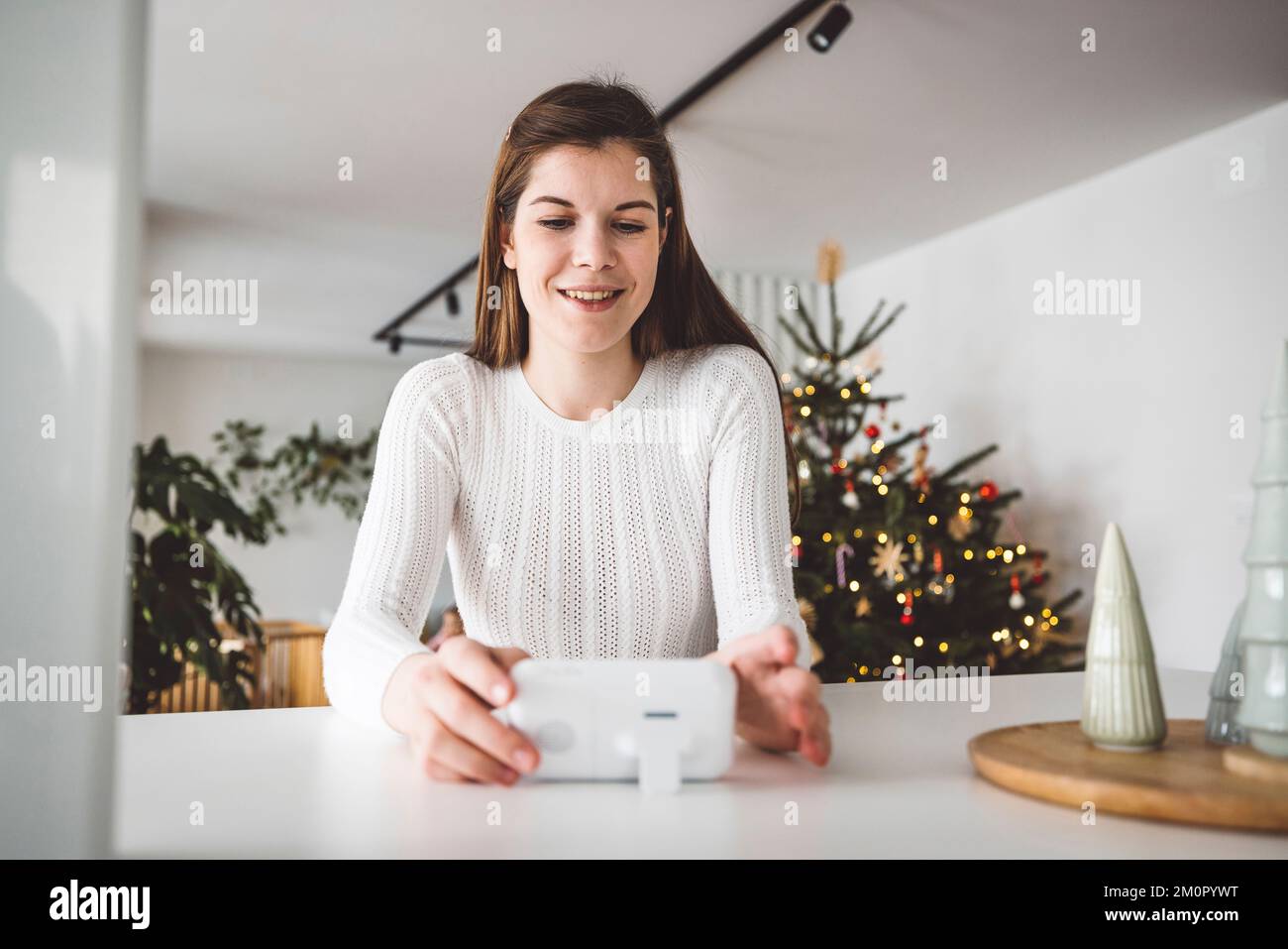 Smiling caucasian woman looking at the baby monitor to see if the baby is still sleeping Stock Photo