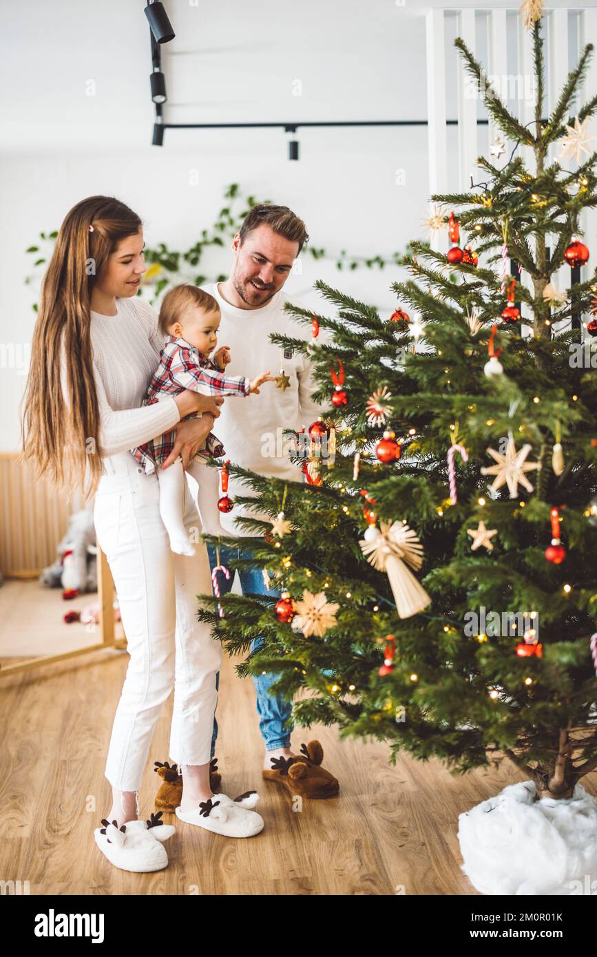 Vertical family portrait of young caucasian family decorating the Christmas tree Stock Photo