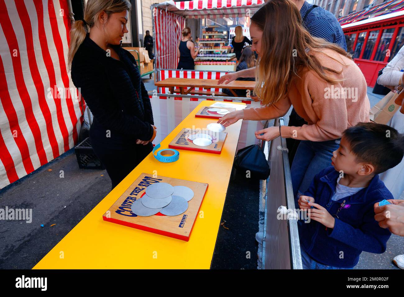 People playing Cover the Spot carnival game at the Chelsea Market 25th Anniversary street fair, New York Stock Photo