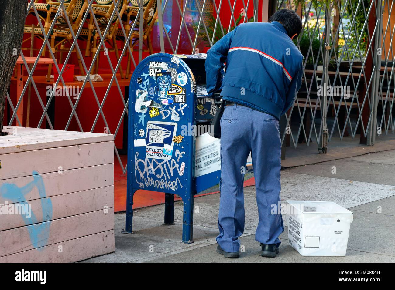 A Postal Service mail carrier collects letters from a collection box in New York City. Stock Photo