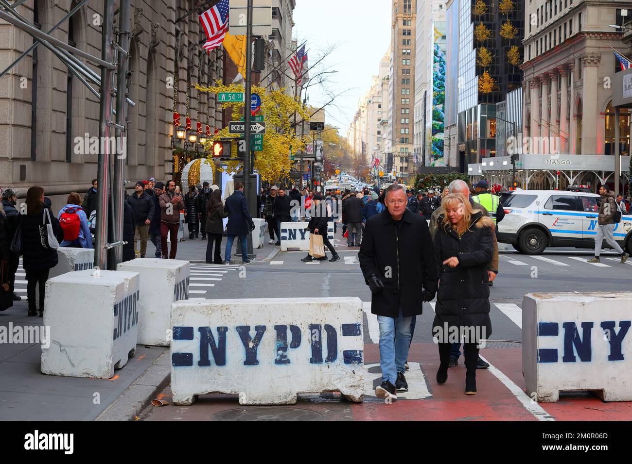 People walking through a NYPD concrete barrier to deter truck attacks during Open Streets Sunday on Fifth Ave, New York, December 4, 2022. Stock Photo
